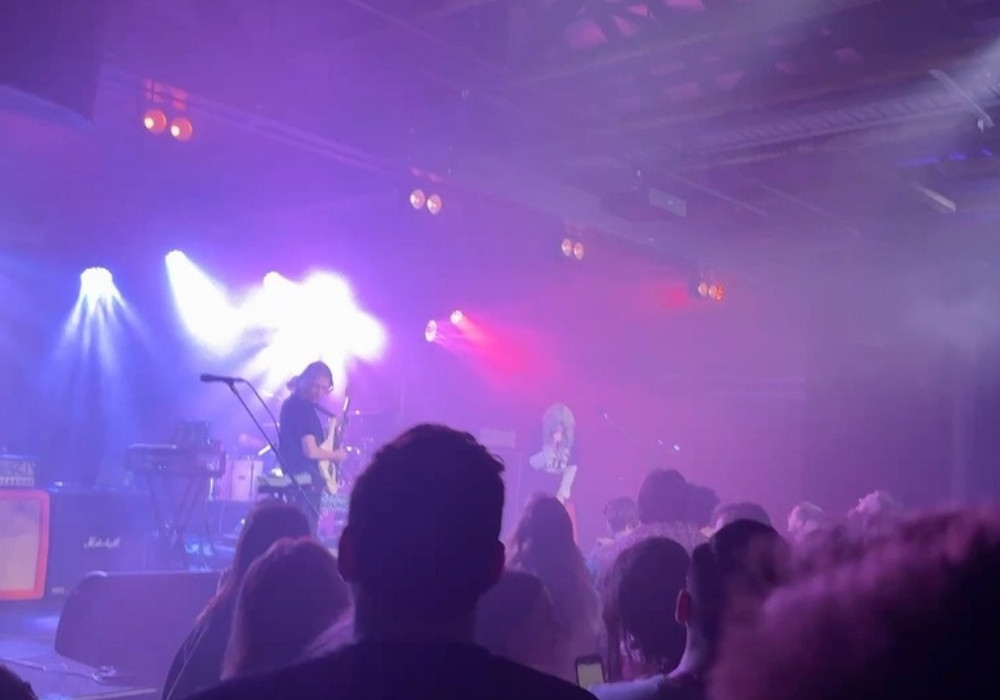 Band on stage with purple haze and a crowd